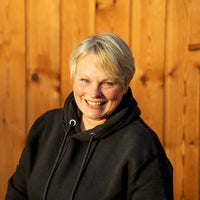Person wearing a black hoodie standing in front of a wooden fence