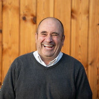 Man smiling in front of a wooden fence